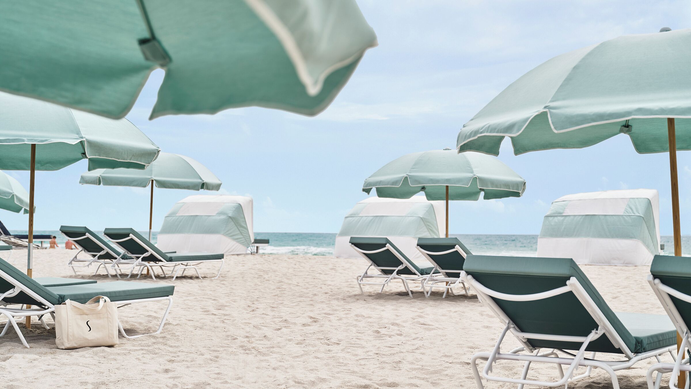 A beach with rows of sun loungers and umbrellas.