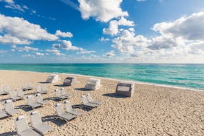 On the beach, white sand, beach cabanas, sun loungers