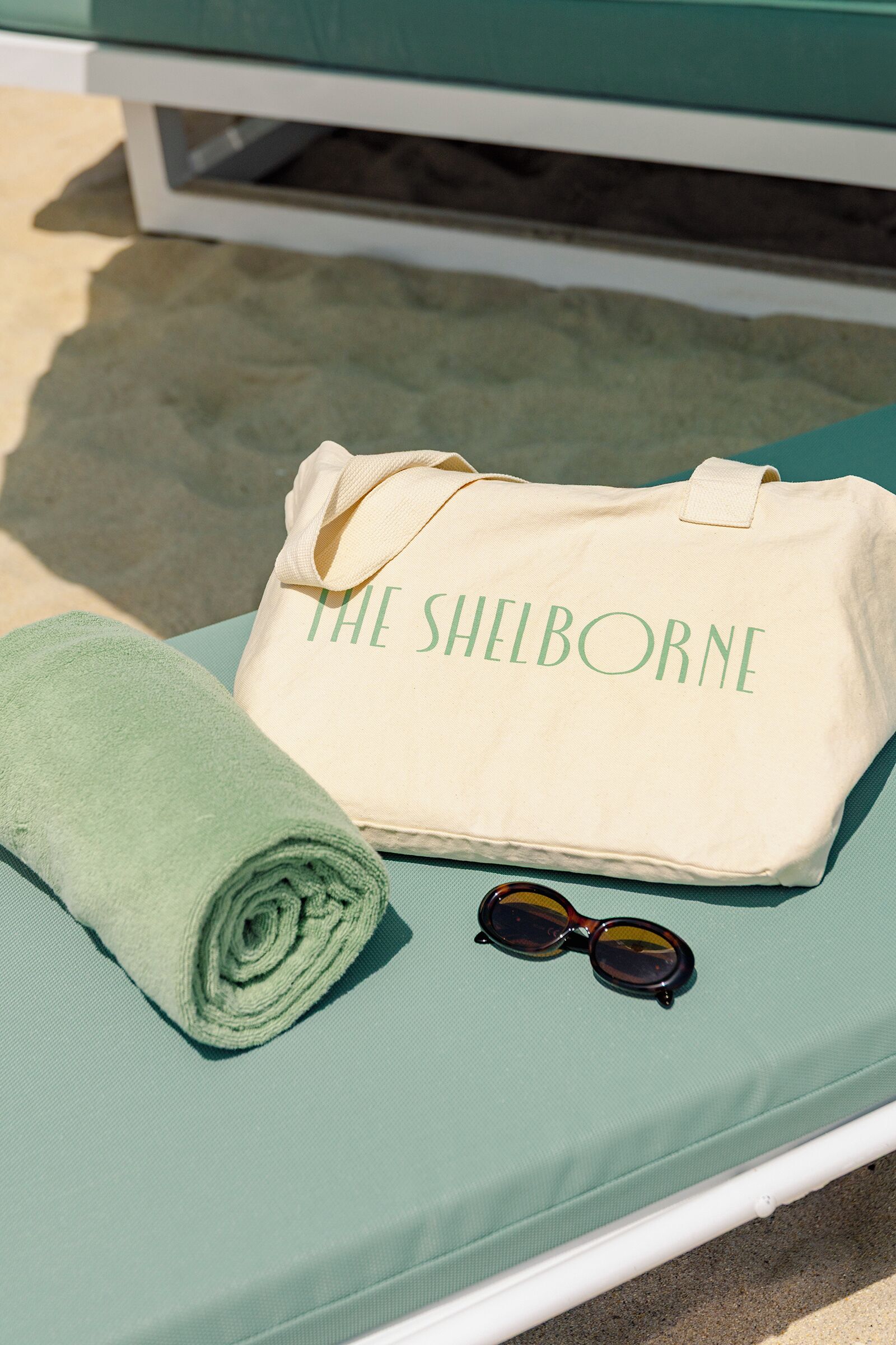 A beach chair with a towel, a bag, and sunglasses.