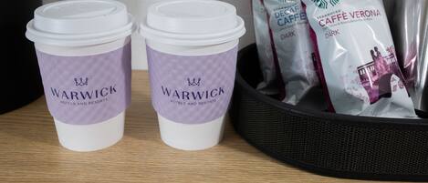 Two disposable cups labeled 'Warwick Hotels and Resorts' and two Starbucks coffee bags labeled 'Dark Caffe mocha'.