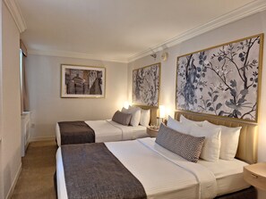 A hotel room with two beds, a large framed cityscape picture, and two large floral wall art pieces. - Warwick Allerton - Chicago (Chicago)
