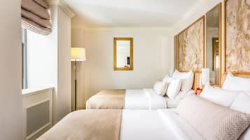 Ein Hotelzimmer mit zwei Betten, einem großen Spiegel und einer Stehlampe.