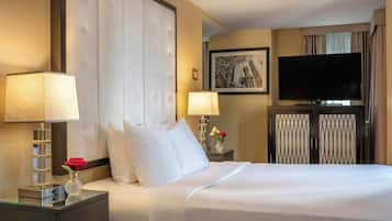Een hotelkamer met een groot bed, twee nachtkastjes met lampen, een flatscreen televisie en een lijst aan de muur.