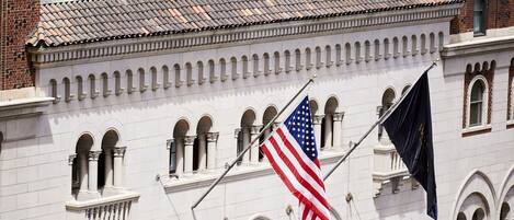 A historic building with a white facade, arched windows, and a large American flag.