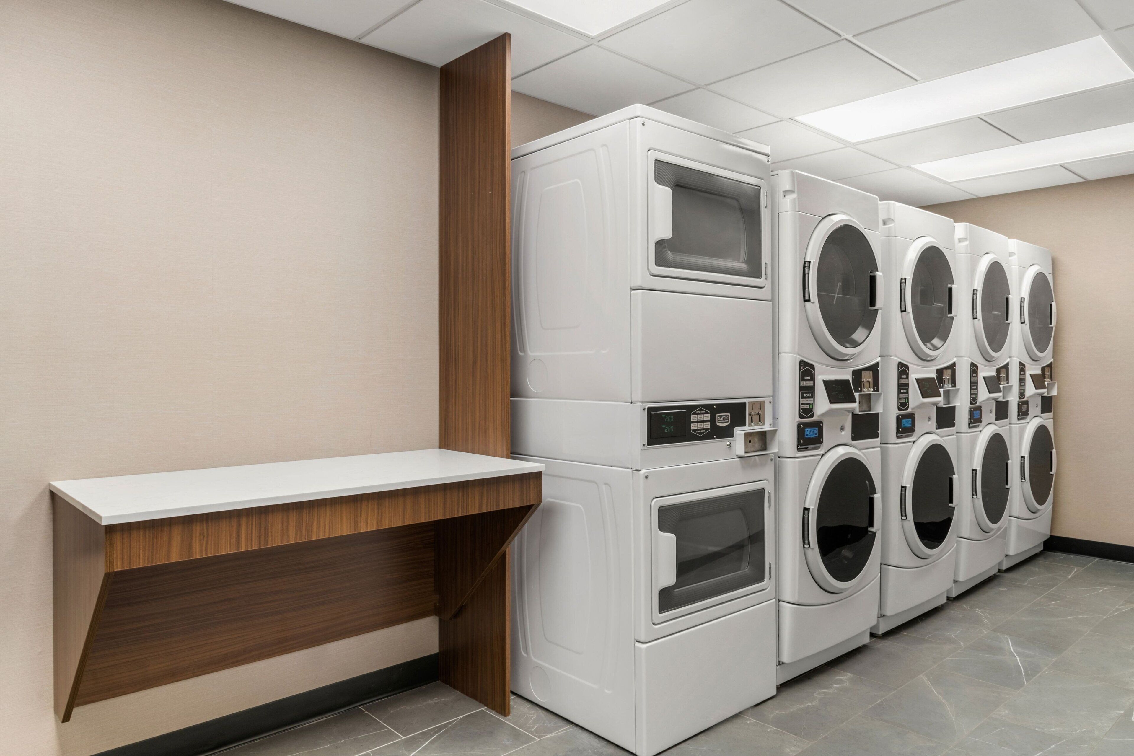 A laundry facility with multiple washing machines and a wooden bench.