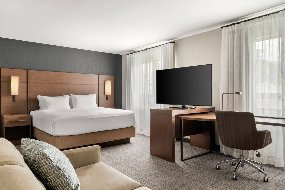 A hotel room with a bed, a desk, a TV, and a sofa.