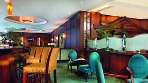 A bar area with wooden bar counters and multiple seating options including bar stools and cushioned chairs. - Cairo Pyramids Hotel (Giza)