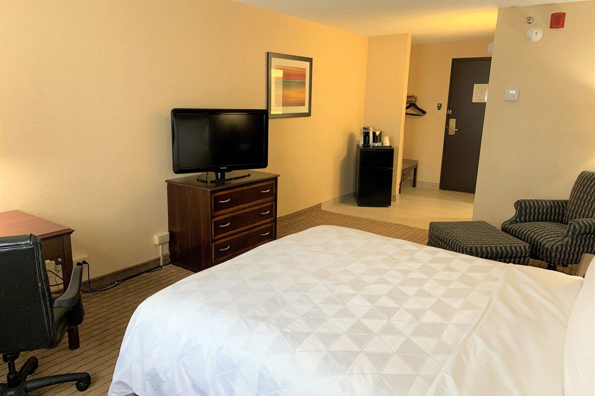Een hotelkamer met een bed, een televisie, een bureau en een stoel.