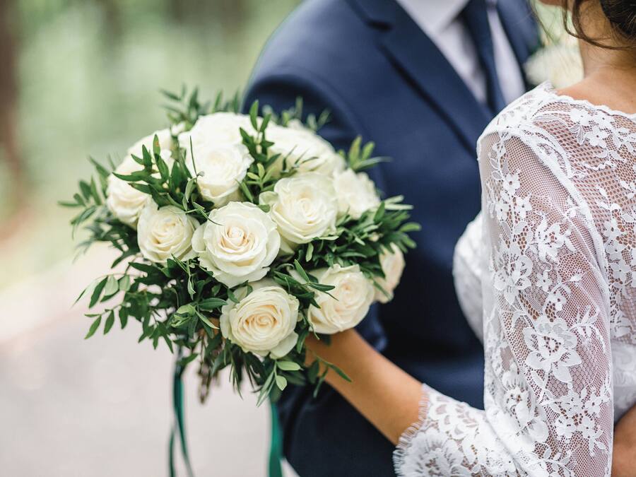 Una persona sostiene un ramo de rosas blancas.