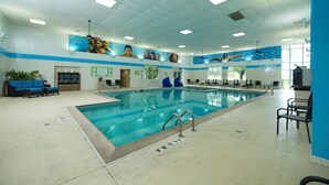 An indoor swimming pool with clear water, surrounded by lounge chairs and a ceiling fan. - Holiday Inn & Suites Chicago-Carol Stream (Wheaton) by IHG (Carol Stream)