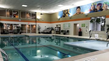 An indoor swimming pool with a lounge area, seating, and a clock on the wall.