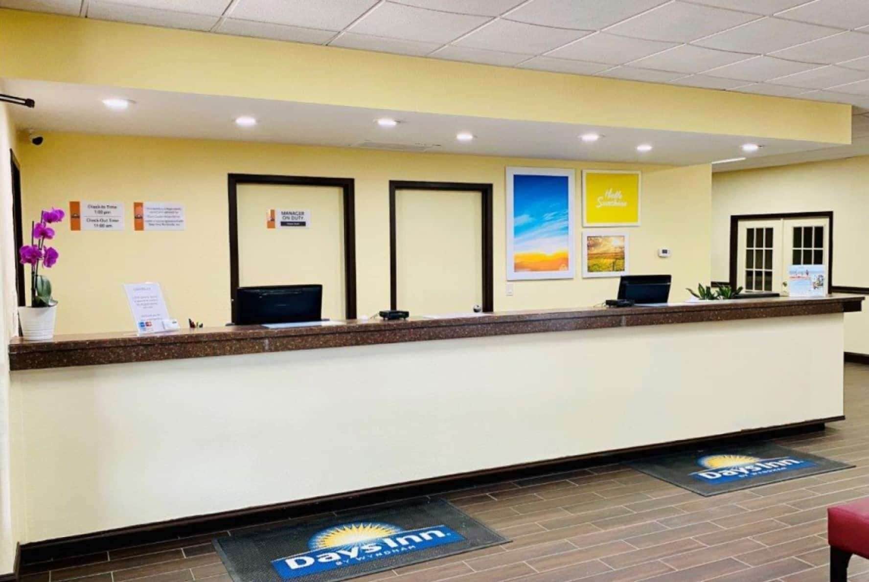 A reception desk with a check-in counter, a digital display, and a sign indicating manager availability.