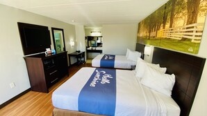 Una habitación de hotel con dos camas, un escritorio, un aparador y una televisión.