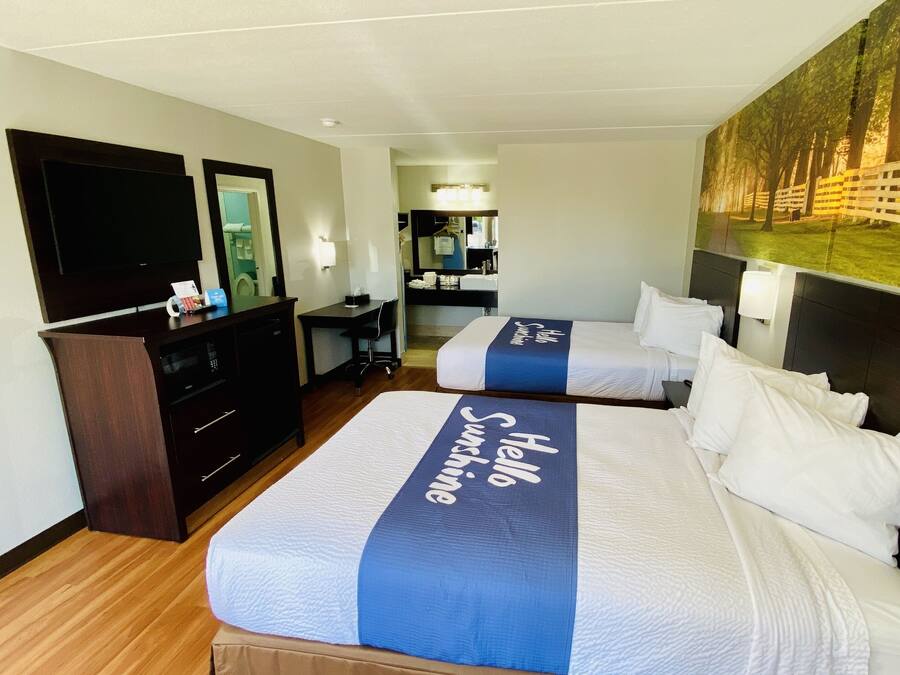 Une chambre d’hôtel avec deux lits, un bureau, une commode et une télévision.