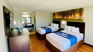 Habitación de hotel con dos camas, un escritorio y un televisor.