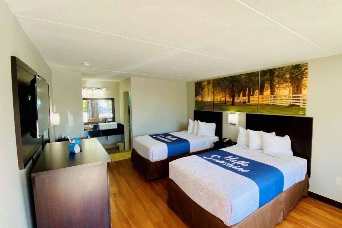 A hotel room with two beds, a desk, and a TV.