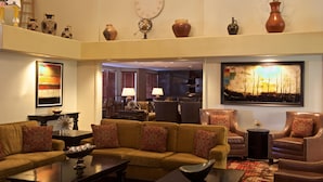 A spacious living area with a sofa set, armchairs, a coffee table, and a dining area in the background.