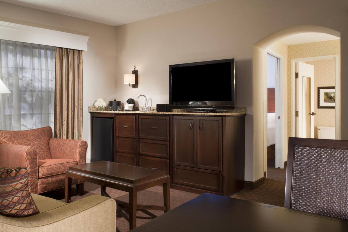 Ein Hotelzimmer mit einer Couch, einem Sessel, einem Fernseher und einem kleinen Tisch.