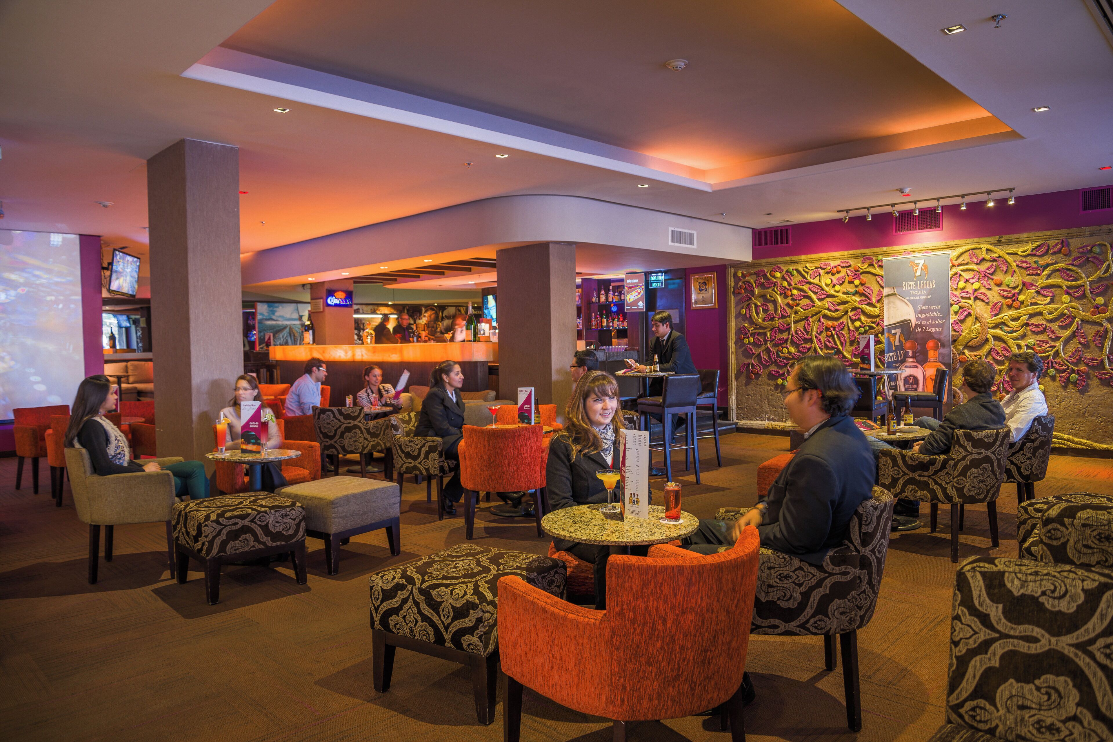 A lobby area with seating arrangements, a bar, and a wall with a textured design.