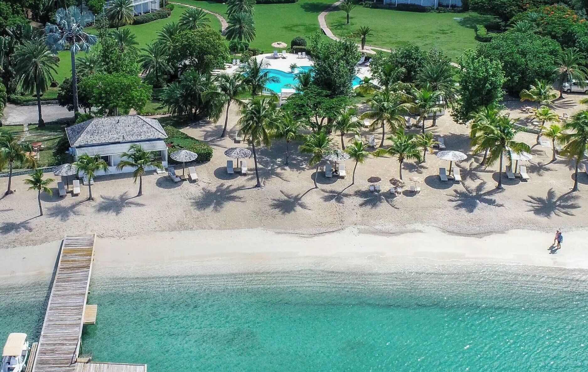 Een resort met een zwembad, palmbomen en een strand.