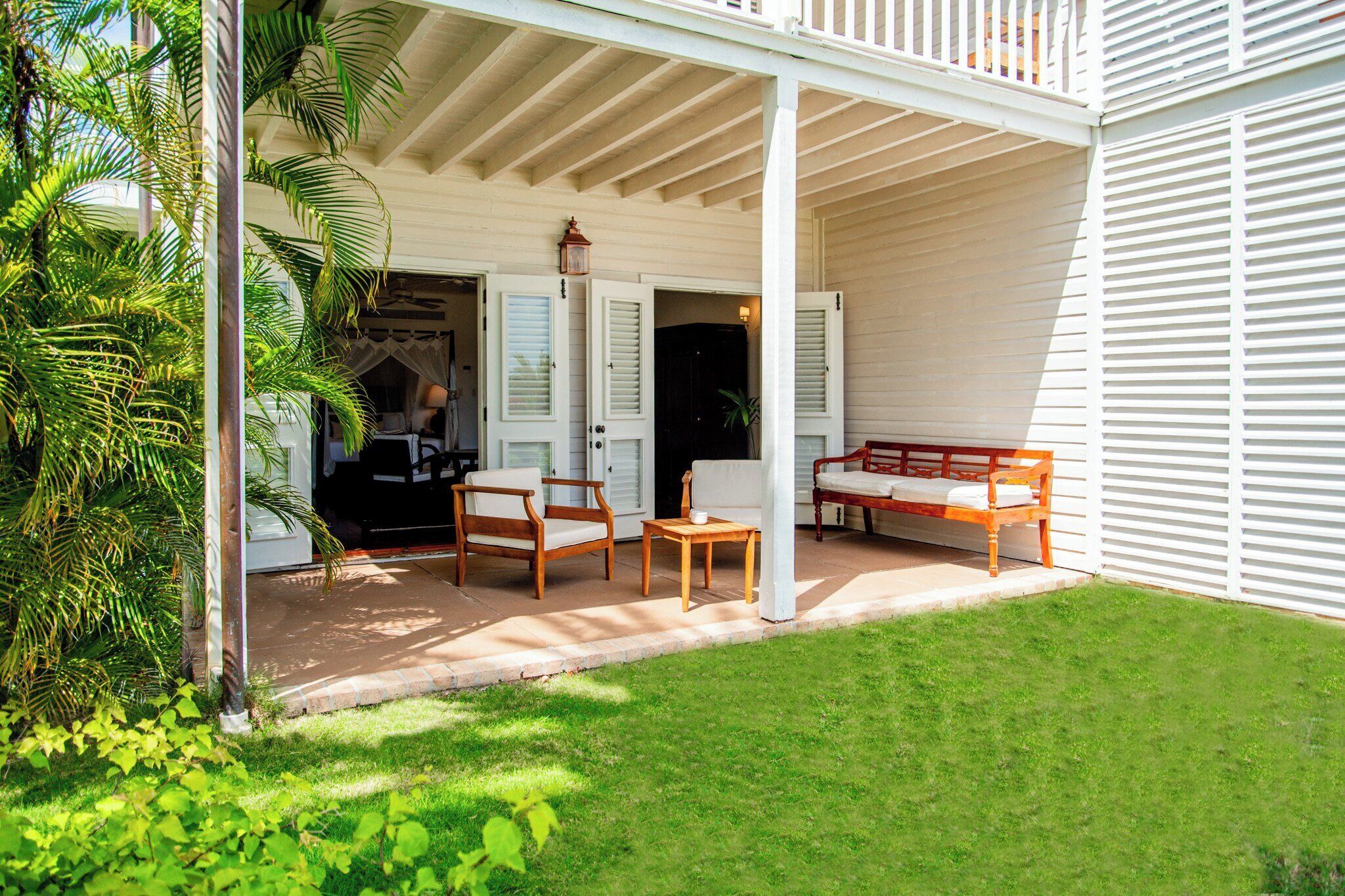 A covered patio with outdoor furniture, a door leading to the interior, and a well-maintained lawn.