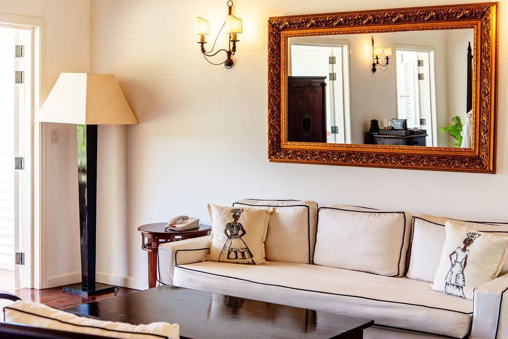 A living room with a sofa, a lamp, a mirror, and a small table with a phone.