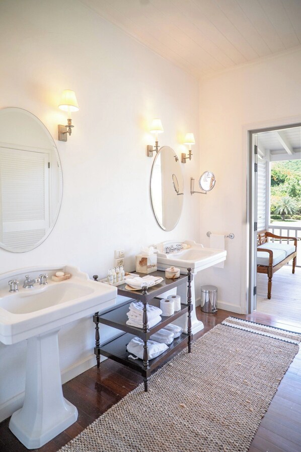 A bathroom with two sinks, a mirror, and a shelf with towels.