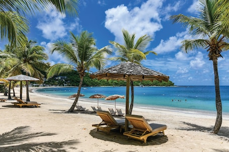 En la playa, arena blanca, sillas reclinables de playa, sombrillas