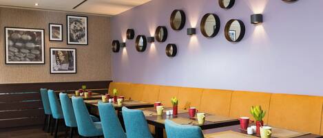 A restaurant with multiple tables, chairs, and wall-mounted mirrors.