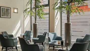 Een zithoek met moderne stoelen en hoge plantenbakken met groene begroeiing.