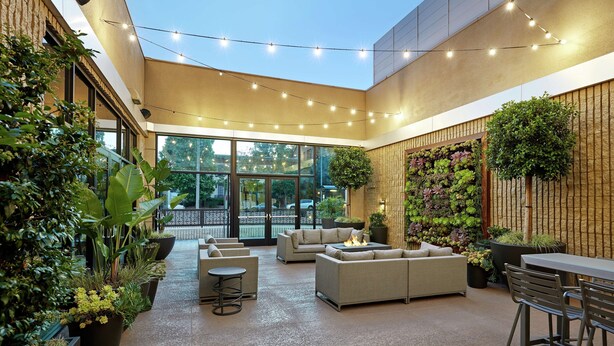 Een ruim buitengebied met moderne zitplaatsen, een vuurplaats en diverse planten.