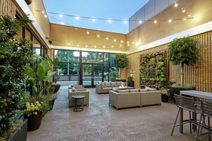 Un amplio espacio al aire libre con mobiliario moderno, una chimenea y diversas plantas.