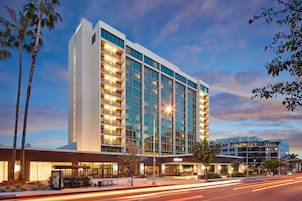 Un hotel moderno con un llamativo letrero de "Hilton", varios pisos y una fachada bien iluminada.