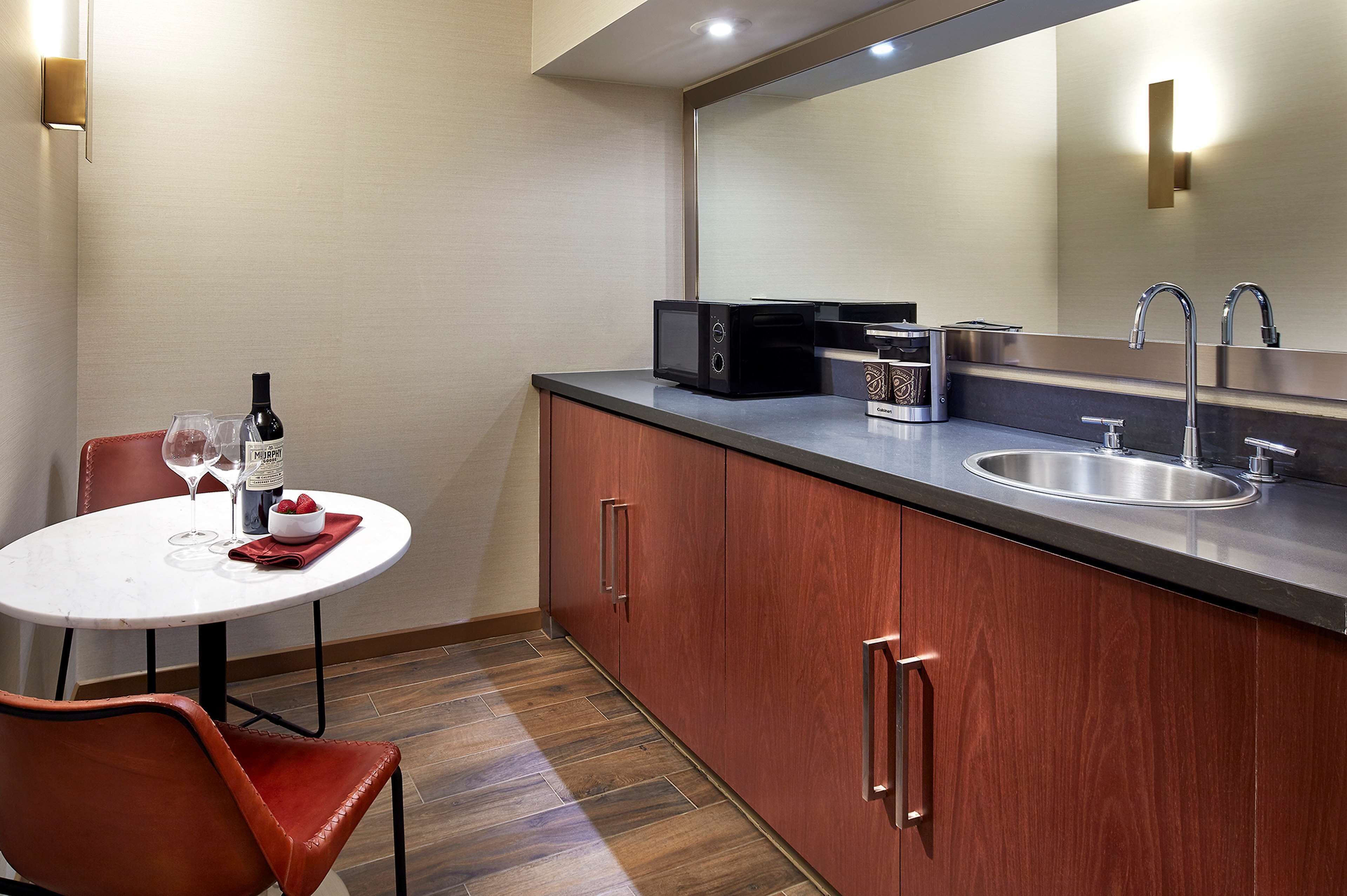 A compact kitchen with a microwave, sink, and a dining area with a table and chair.