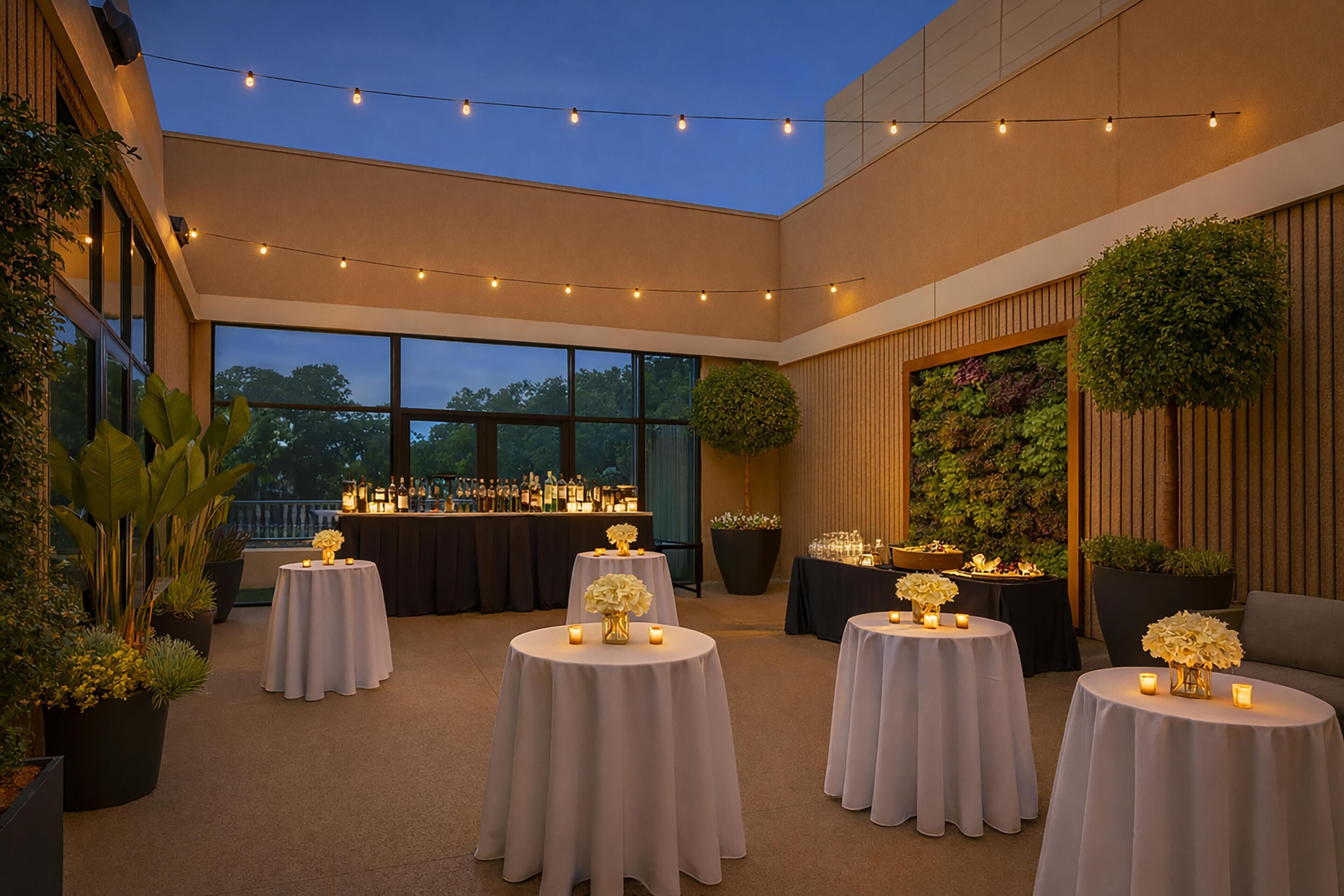 An outdoor patio area with round tables, string lights, and potted plants.