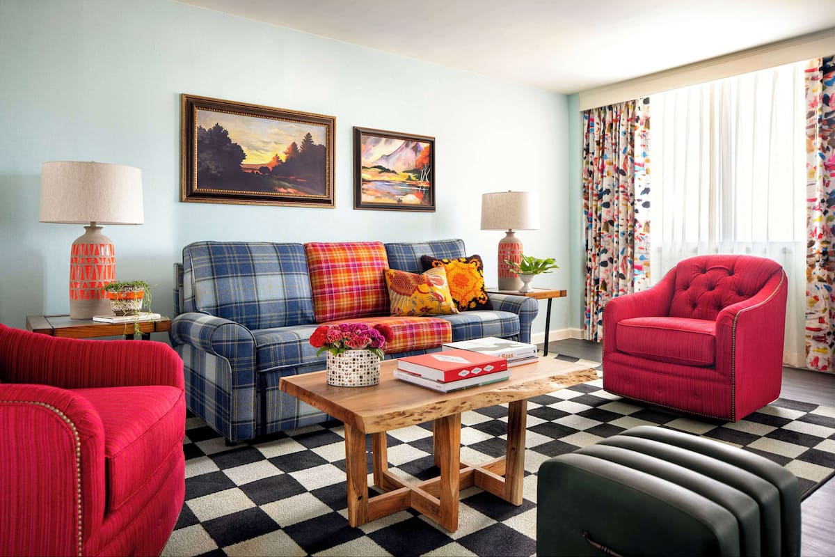 A living room with a checkered floor, a sofa, a red armchair, and two lamps.
