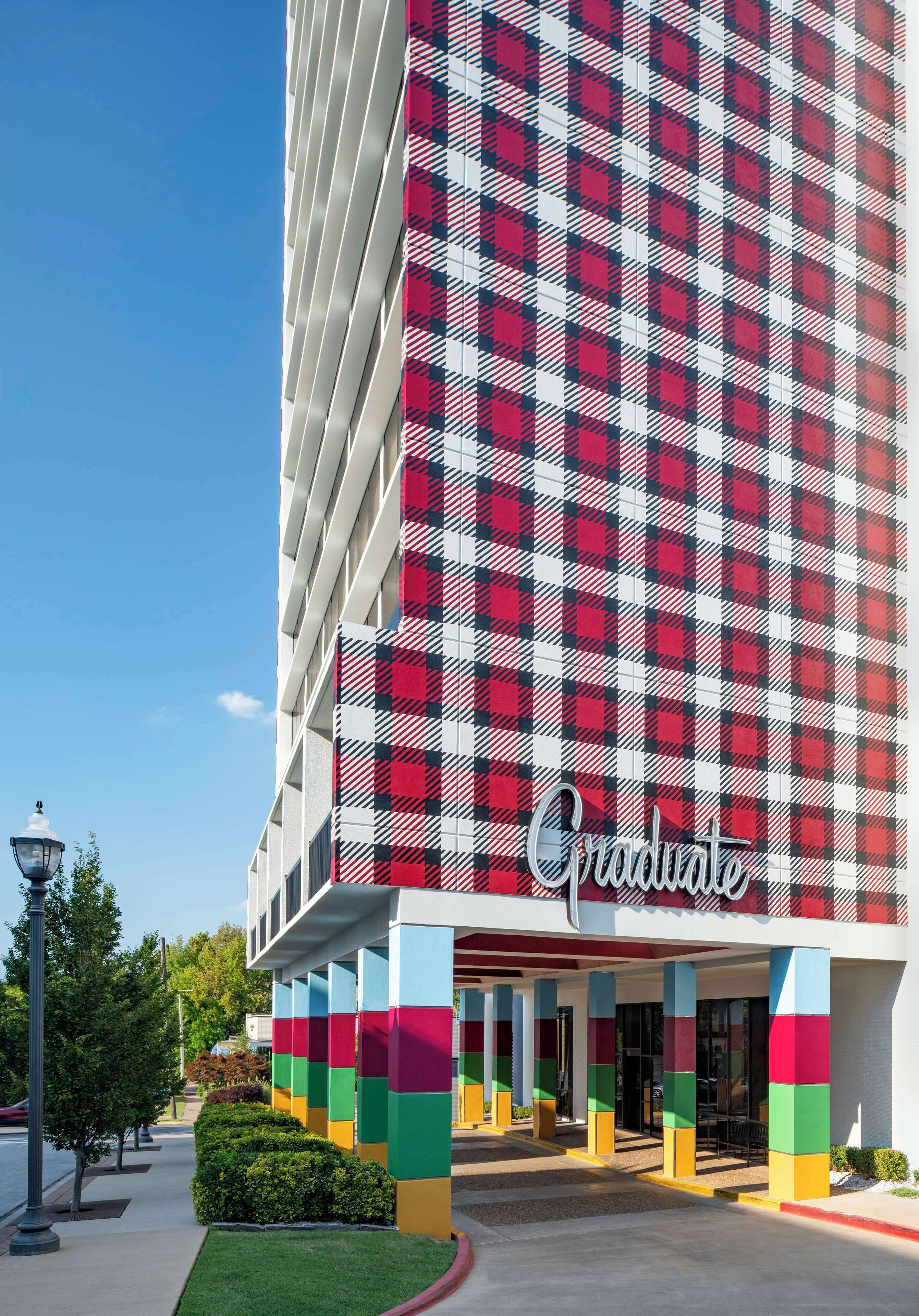Un hotel con facciata a quadri rossi e bianchi, una base colorata e la scritta 'Graduate' all'ingresso.