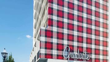 Ein Hotel mit rot-weiß kariertem Mauerwerk, einem farbenfrohen Sockel und dem Schriftzug „Graduate“ am Eingang.