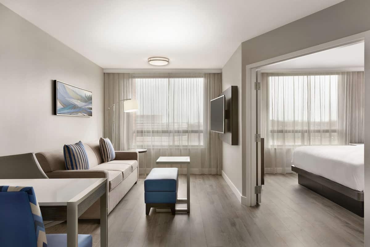 Ein modernes Hotelzimmer mit einer Couch, einem kleinen Tisch, einem Fernseher und einem Bett.