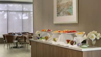 Montaje de bufé con diversos alimentos y un área de comedor con mesas y sillas.