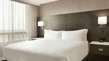 Habitación de hotel con una cama grande, dos mesitas de noche y una mesita auxiliar con un reloj.