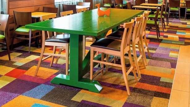 A conference room with a long table, chairs, a television, and a colorful carpet. - Fairfield Inn & Suites by Marriott Springfield (Springfield)