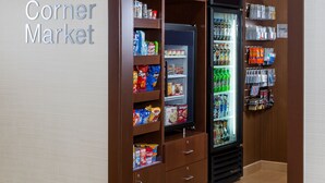 A Corner Market with shelves stocked with snacks, a refrigerated section, and a display of bottled water and other beverages. - Fairfield Inn & Suites by Marriott Springfield (Springfield)