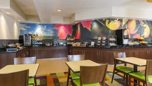 A modern kitchen with a mural, a coffee station, and seating area.