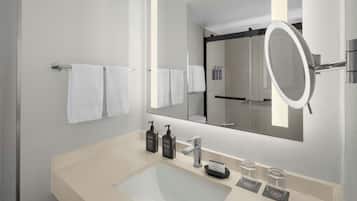 A modern bathroom with a large mirror, a sink, and two bottles of soap.
