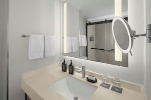 Un baño moderno con un espejo grande, un lavamanos y dos botellas de jabón.