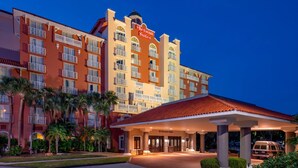 A Sheraton Suites hotel with a red and beige facade, multiple balconies, and a covered entrance.