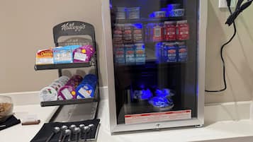 En försäljningsautomat fylld med olika typer av snacks och drycker, inklusive Kellogg’s-flingor och McArthur’s mjölkförpackningar.