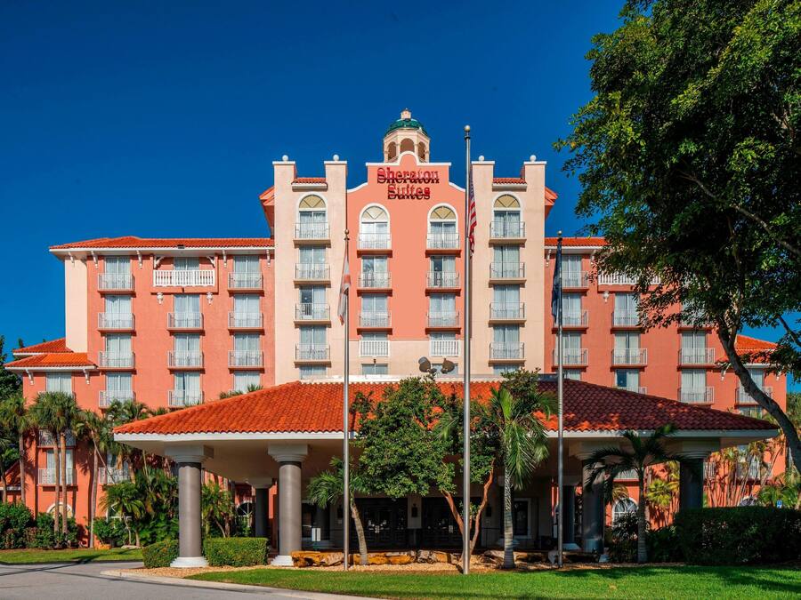 A hotel with a red facade, multiple balconies, and a sign reading "Sheraton Suites".