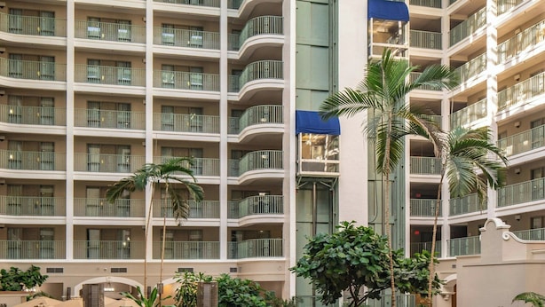 A multi-level hotel atrium with balconies, seating areas, and a central rock feature.